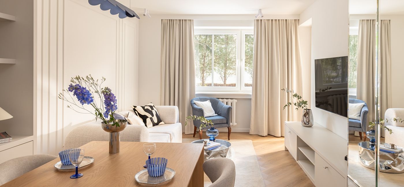 Jasny salon z jadalnią, lustrzaną szafą i designerską lampą w odcieniu burzowego błękitu
