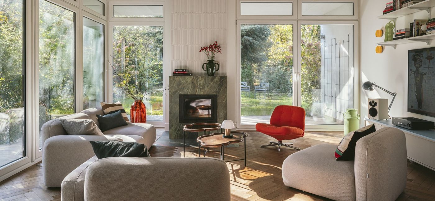 salon w stylu modern retro z  kominkiem obłożonym zielonym marmurem