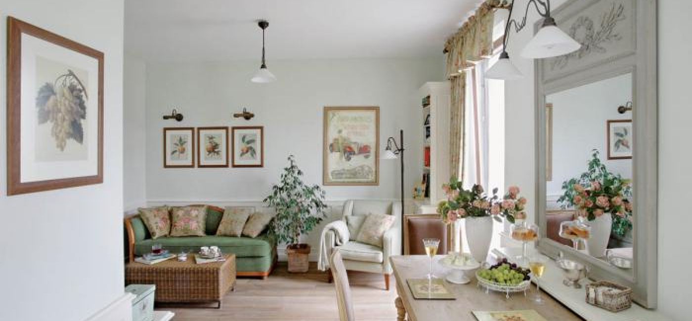 Na zielonej kanapie leżą poduszki obszyte tkaniną w róże.