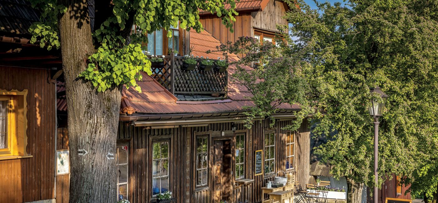 Niskie drewniane domy z charakterystycznie ściętym i dachami otaczają pochyły rynek. To dzięki nim w