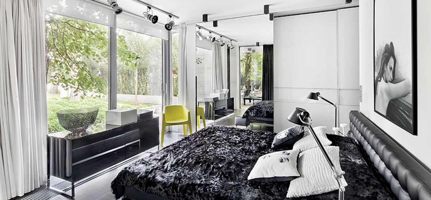 Sypialnia z panoramicznym oknem i dizajnerskimi smaczkami: stojace lampy Tolomeo (marki Artemide), czy poduszki z