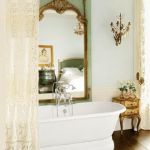 Romantyczna łazienka z koronkową zasłoną. W ogromynym weneckim lustrze odbija się Biała sypialnia.