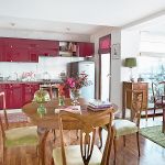 Kolorowe nowoczesne meble w kuchni współgrają z naturalnym drewnem starego stołu.