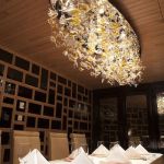 Kompozycja szklano-świetlna nad stołem w jadalni, wykonana z ręcznie formowanych, kolorowych elementów szklanych