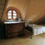 Obok łóżka stoi drewniana komoda. Wymarzone miejsce