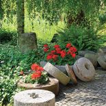 amienne żarna, dawniej służące do mielenia zboża, zostały przerobione na donice dla jaskrawoczerwonych pelargonii.