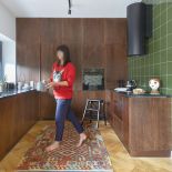 Gładkie fronty szafek z litego drewna tworzą jednolitą płaszczyznę, która niczym boazeria opiela kuchnię. Nad