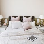 Na ścianie tapeta zaprojektowana przez Williama Morrisa. Różowe poduszki – BoConcept, pozostałe i futerkowy pled – BBHome.
