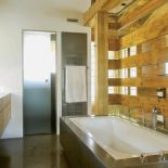 azienkę z sypialnią Barry ego łączy ażurowa ścianka z grubo ciosanych belek. Podłoga i obudowa wanny są zrobione z lokalnego