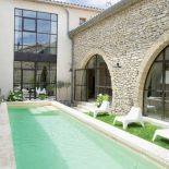 Basen ma 9 metrów, pas trawy, dookoła stoją terakotowe donice z hortensjami i bukszpanem.