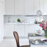 Biała drewniana podłoga, białe ściany i biała kuchnia - jak przystało na styl skandynawski w mieszkaniu Na takim tle