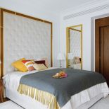 Sypialnia dzięki pikowanemu zagłówkowi w ramie z drewna i mosiądzu oraz lampie z łańcuszków ma lekko pałacowy styl.