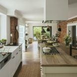 biała kuchnia z drewnem i czerwoną cegłą