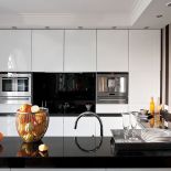 Biało-czarna nowoczesna kuchnia wycisza rozmach reszty domu. Nie brak w niej ciepłuch akcentów: pasiastej tapety