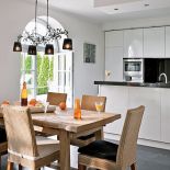 Biało-czarna nowoczesna kuchnia wycisza rozmach reszty domu. Nie brak w niej ciepłuch akcentów: pasiastej tapety