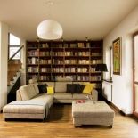 Biblioteka marzeń właścicieli - z przepastnym regałem fornirowanym ciepłym drewnem orzechowym i wygodną kanapą w