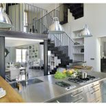 Na granicy między kuchnią a jadalną znajdują się ażurowe, loftowe schody, spawane na miejscu przez