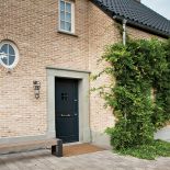 Ceglana elewacja, czarny spadzisty dach i minimalistyczny ogród.