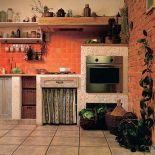 Ceglana ściana i murowane szafki kuchenne sprawiają, że czujemy się tu jak na wsi.