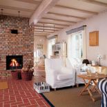 Chata ma tylko 90 metrów kwadratowych. Jaśniutkie kolory i otwarta przestrzeń parteru sprawiają, że wydaje