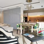 Chłodny kamień i fronty na wysoki połysk ocieplaja krzesła obite lnem marki Christopher Farr.