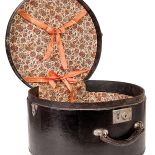 Skórzana walizka na kapelusz z podszewką w kwiaty.