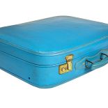 Turkusowa walizka z pozłacanymi klamrami.