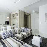 Ciekawa ściana wykończona drewnem jest kontynuacją przedpokoju. Białym akcentem jest fantazyjnie wygięty stolik kawowy.