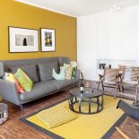 Ciepły palisandrowy parkiet i miodowa ściana. Do tego dizajnerskie meble. Sofa z Vitry, lampa marki