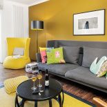 Ciepły palisandrowy parkiet i miodowa ściana. Do tego dizajnerskie meble. Sofa z Vitry, lampa marki