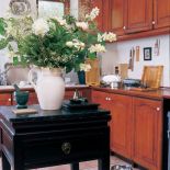 Czarny stolik z drewnianym blatem na środku kuchni sprawia, że z jadalni nie widzimy kuchennego rozgardiaszu.