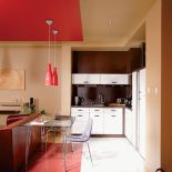 Czerwone meble, podłogi i sufit tworzą w salonie kolorową wyspę . Jej częścią jest mozaika. Stół i krzesła są przezroczyste,