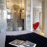 W łazience beton na ścianach i wielka tafla szkła (jednocześnie obrotowe drzwi) oddzielająca prysznic od sypialni. Odważnie i ciekawie.
