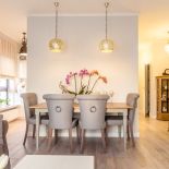 Część jadalna w salonie: stół z krzesłami w pięknej tapicerce i z uchwytami na tylknej części oparć.