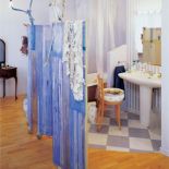 Część sypialną od kąpielowej dzieli tylko parawan pokryty błękitną tkaniną.