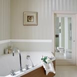 Dekoracyjna listwa na ścinie i tapeta w subtelne pasy dodają łazience elegancji.