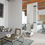 Do czerwieni cegły pasują stonowane dodatki. Szary pled, poduszki we wzór marokańskiej koniczyny i te