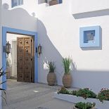 Drewniana brama ozdobiona elementami z kutego żelaza prowadzi na mały dziedziniec wyłożony betonem i kostką brukową.