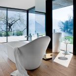 Drewniana podłoga, szklana ściana i drewniany taras. Łazienka zaprojektowana przez Ludovicę i Roberta Palombów. Umywalka