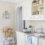 Drewniane bielone meble z delikatnymi przecierkami i piec marki La Cornue ze srebrno-miedzianymi dodatkami z