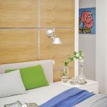 Drewniane kwadraty ułożone za łóżkiem stylistycznie nawiązują do elegancji stylu międzywojennego.