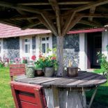 Drewniany parasol zakrywa stół i krzesła.