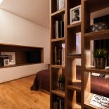 Drewniany regał na książki oddziela najbardziej intymną część sypialni od wejścia.