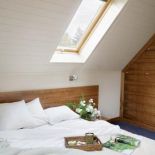 Duże łóżko w jasnej sypialni. Poddasze w angielskim nastroju