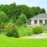 Duży dom w stylu amerykańskich rezydencji znika w bujnej zieleni.