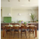 Duży rodzinny stół stoi między kuchnią a salonem.