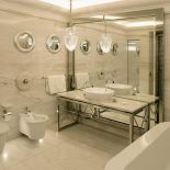 Dziecięca łazienka, jak na Titanicu – luksusowa armatura, piaskowy marmur, okrągły kaloryfer i lustra-bulaje.