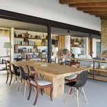Eklektyczna jadalnia: betonowa podłoga, drewniany stół, artdecowskie i nowoczesne krzesła.