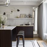 kuchnia z ryflowaną wyspą z ciemnego drewna i kamiennym dywanem na posadzce