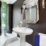 Elegancka, z przykuwającą uwagę ciemnobrązową ścianą, na której wisi lustro w artdecowskiej ramie.